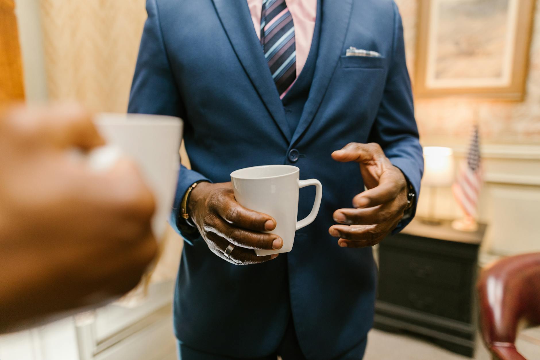 man in blue suit holding white ceramic mug